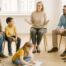 Mehrere Familien sitzen gemeinsam in einem Stuhlkreis und tauschen sich in einer Gruppensitzung aus